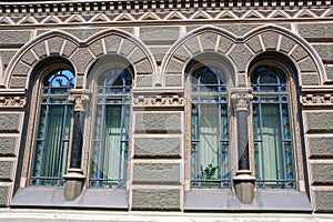 Two old windows on a gray wall of a stone house