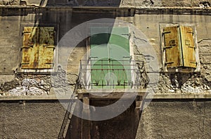 Two old windows and a green balcony door on the old building