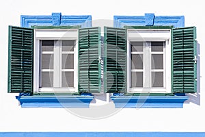 Two old windows with green wood shutters