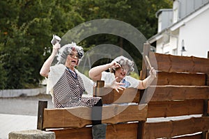 Two old Women shouting over the garden fence