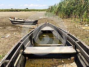 Two old wooden broken boats on the river bank near the reeds. Countryside. The dried river.