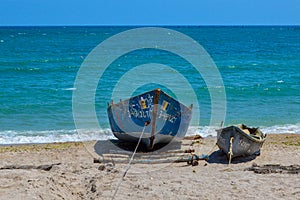Two old wooden row-boats of different sizes on the sandy beach of the Black Sea on a clear, blue sky, sunny summer day