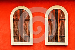 Two old wooden windows on the red wall.