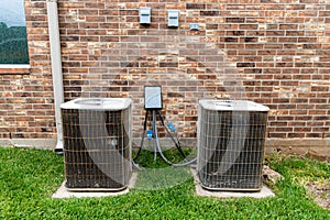 Older HVAC air conditioner units next to brick home with copy space