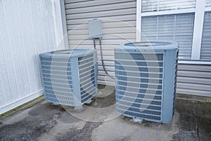 Two Older Air Conditioning Units Behind Rental Condo