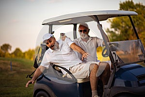 Two older friends are riding in a golf cart