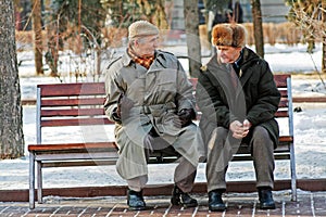 Two older man sitting on the bench in the park and talking in Volgograd