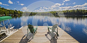 Two Ontario chairs sitting on a wood dock facing a calm lake. photo