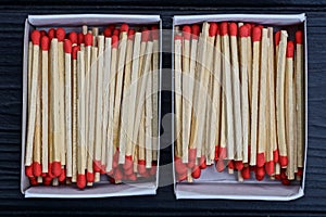 two open paper boxes with gray wooden matches and red heads