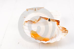 Two open raw scallops, on white wood