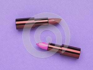 Two open tubes of lipstick on a purple background. Flat lay