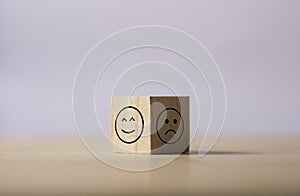 Two opposite side of emotion of happy and sad which print screen on wooden cubic. Customer experience survey and satisfaction