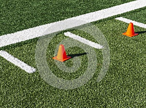 Two orange cones between hash marks on football field