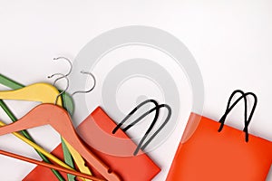 Two orange paper shopping bags with colorful hangers over white background
