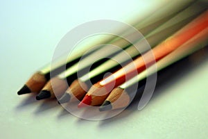 Two orange pencils between black pencils