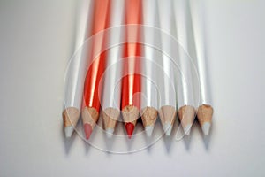 Two orange pencils between white pencils