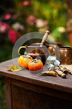 Two orange pumpkins on wooden rustic table with ears of wheat, sackcloth, persimmons, autumn leaves