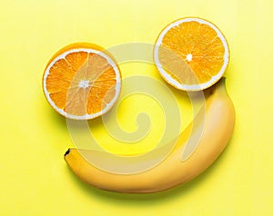 Two orange slices and a banana on a yellow background. the figure looks like a smiley. joke concept and good mood. flat lay