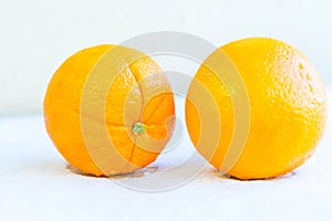 Two orange on snow background. Ripe fruits