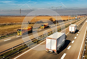 Two Orange Tank trucks or Cisterns on a Highway Road passing white Trucks
