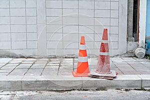 Two orange traffic cones on footpath concrete road.