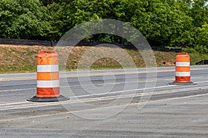 Two orange and white traffic barrels dividing a rural street in a road construction zone, copy space