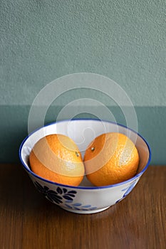 Two oranges fruit on a white ceramic bowl