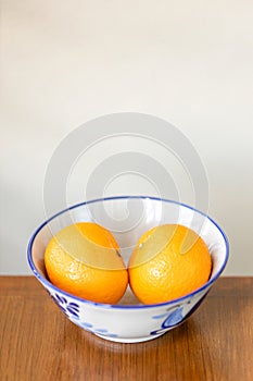 Two oranges fruit on a white ceramic bowl