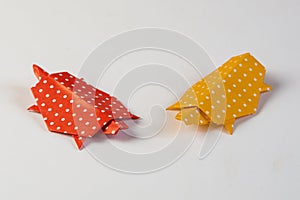Two origami turtles made from red and yellow paper with white dots, isolated on blank background