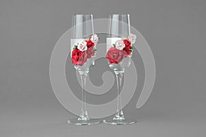 Two ornate wedding wine glasses decorated with red and pink roses.