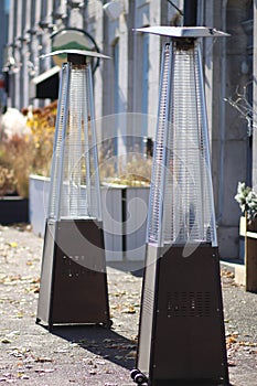 Two outdoor glass heaters placed on a sidewalk photo