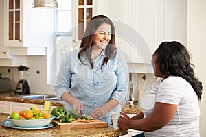 Two Overweight Women On Diet Preparing Vegetables in Kitchen