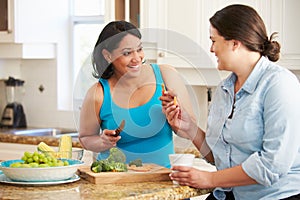 Two Overweight Women On Diet Preparing Vegetables in Kitchen