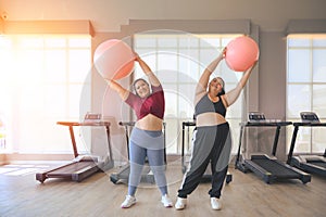 Two overweight women exercise workout in gym. Plus size woman training with fitball. Weight loss workout, healthy lifestyle