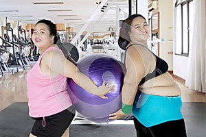 Two overweight women holding a fitness ball