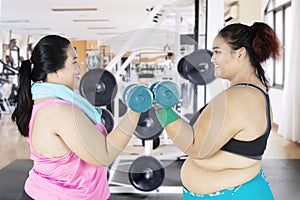 Two overweight women lifting barbells