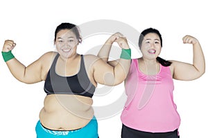 Two overweight women showing their arm muscle