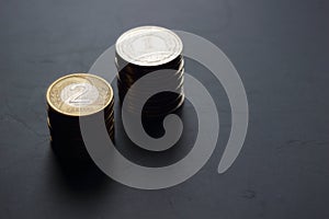 Two packs of Polish zloty coins on grungy dark matte background.