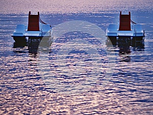 Two paddle boats without people floating on the sea water table in evening light