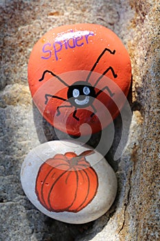 Two painted Halloween rocks of spider and pumpkin