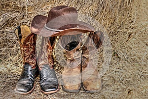 Two pair of cowboy boots and a hat on hay