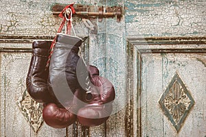Two pair of vintage boxing gloves hanging on a weathered ancient