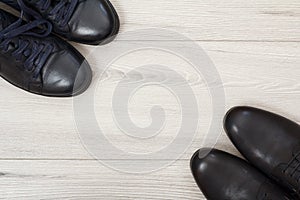 Two pairs of black leather men`s shoes on grey wooden background