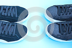 Two pairs of black sneakers on blue neon background