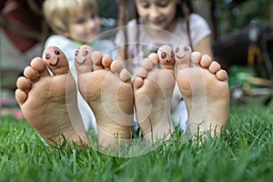 Two pairs of children\'s bare feet on green gras