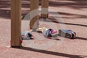 Two pairs of childrens` sneakers lies on the playground