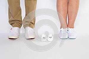 Two pairs of feet from the parents and shoes from an unborn baby