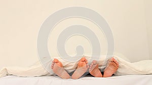 Two pairs of feet under a blanket