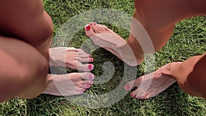 Two pairs of female feet stand opposite each other on the green grass