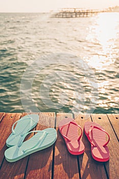 Two pairs of flip flops at the wooden pier during sunset. Luxury vacation resort. Holiday getaway concept